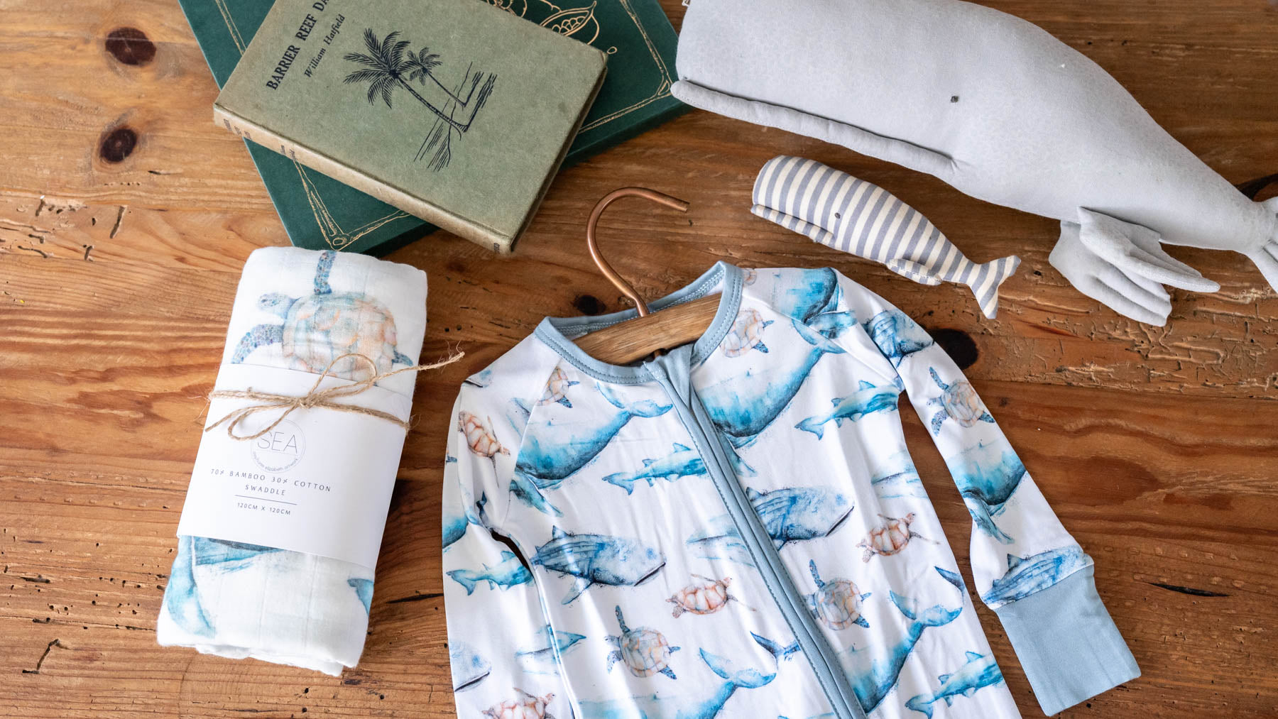 SEA Gallery giftware flatlay of baby swaddle and onsie eco snug romper