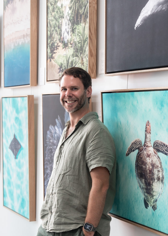 David Lloyd – standing against gallery wall with his canvas photographic artworks displayed behind him | About SEA Gallery