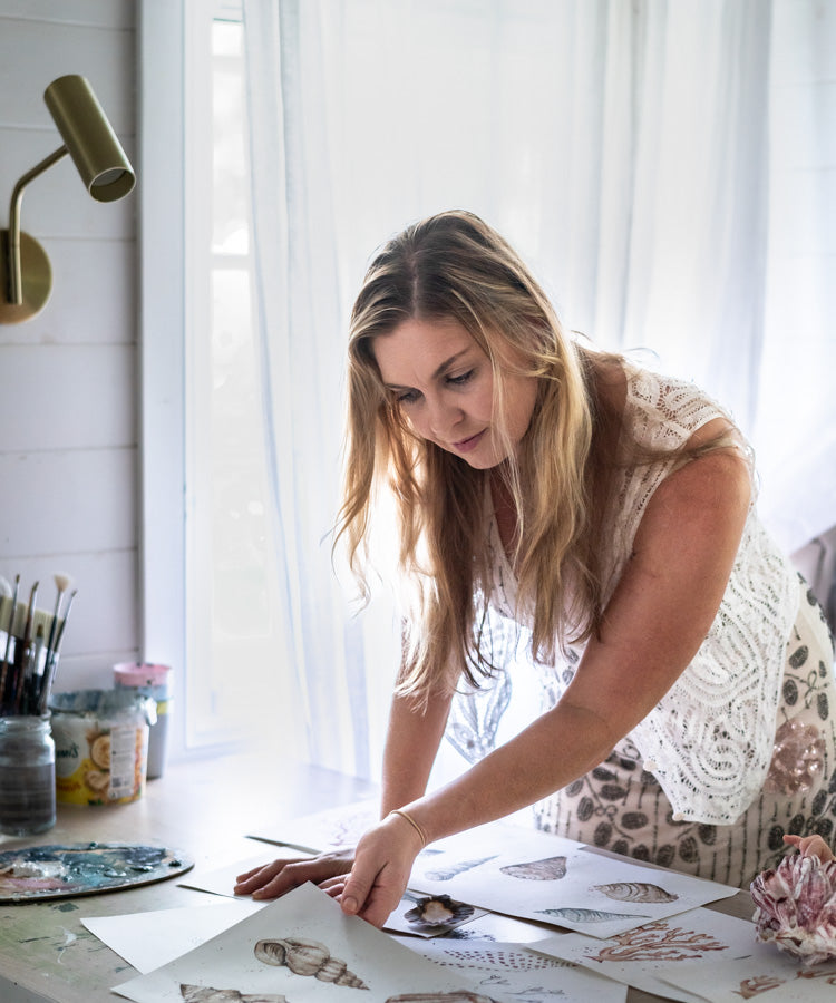 Stephanie Elizabeth looking over her art collections, backlit in her Port Douglas studio | About Page Section “Where It Began”