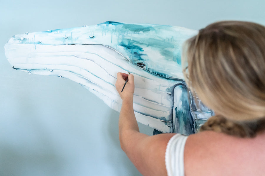 Stephanie Elizabeth painting a humpback whale in her studio, focused on the canvas | About Page Section