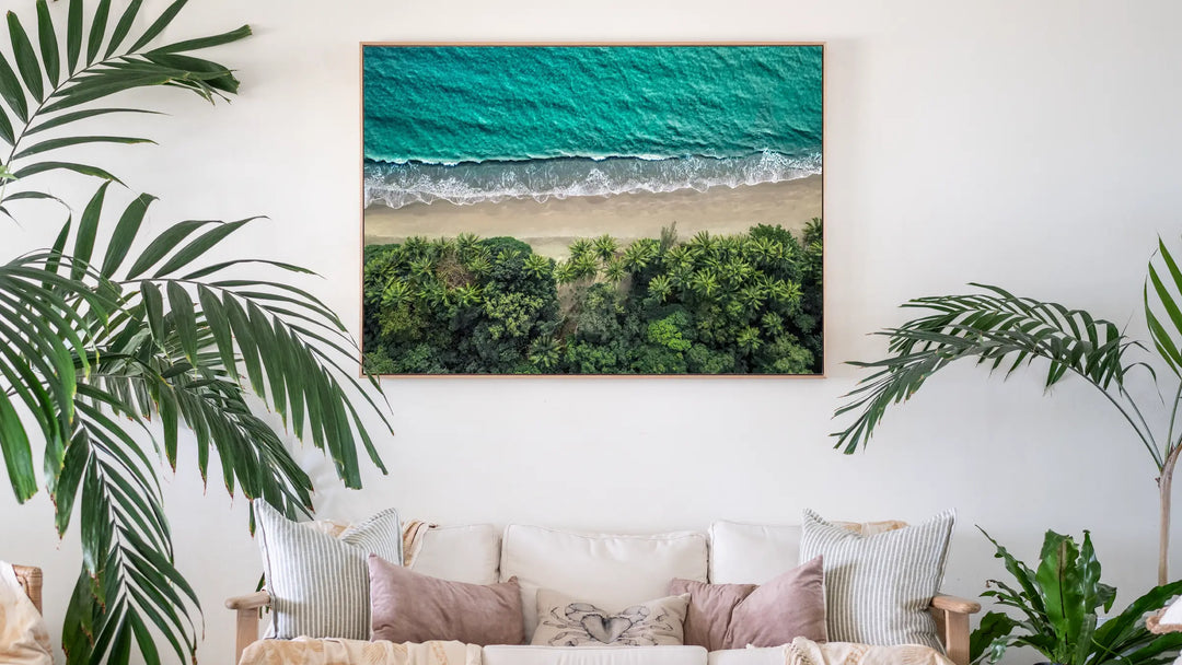 Large framed aerial coastal photography print by David Lloyd displayed in a relaxed tropical interior