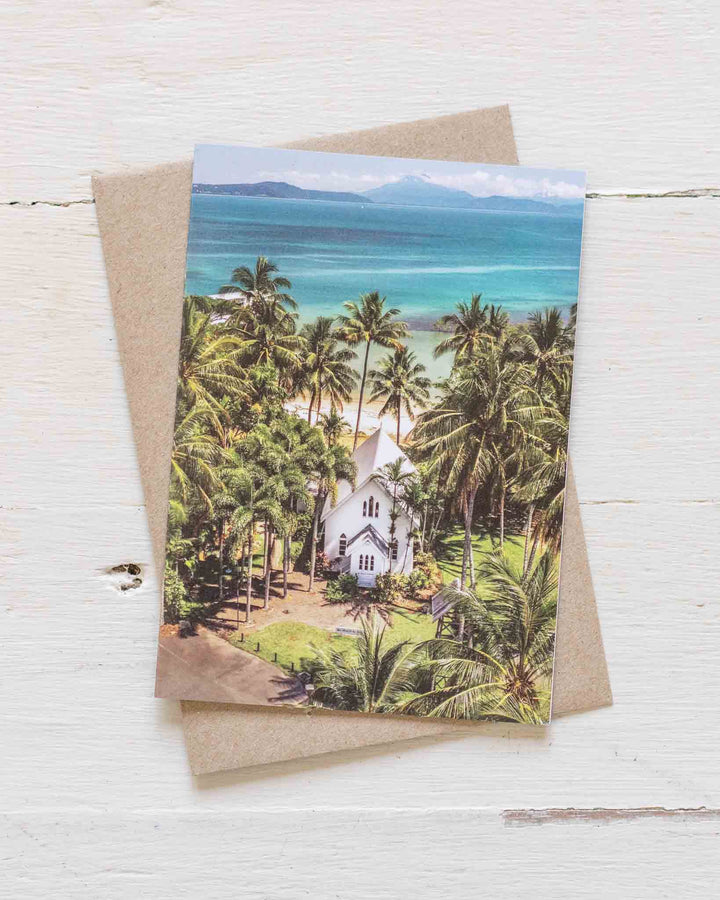 A Slice of Paradise greeting card showing a tropical church and palm trees, displayed with a brown envelope.