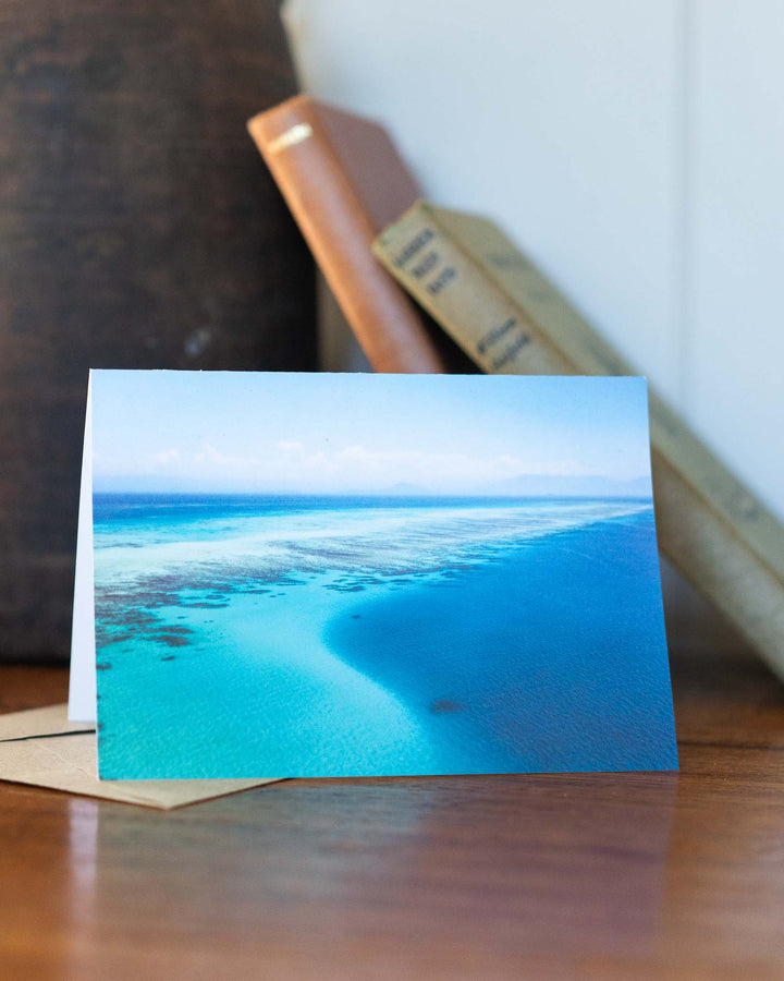 As Far As The Eye Can See greeting card on a table with blurred books in the background.