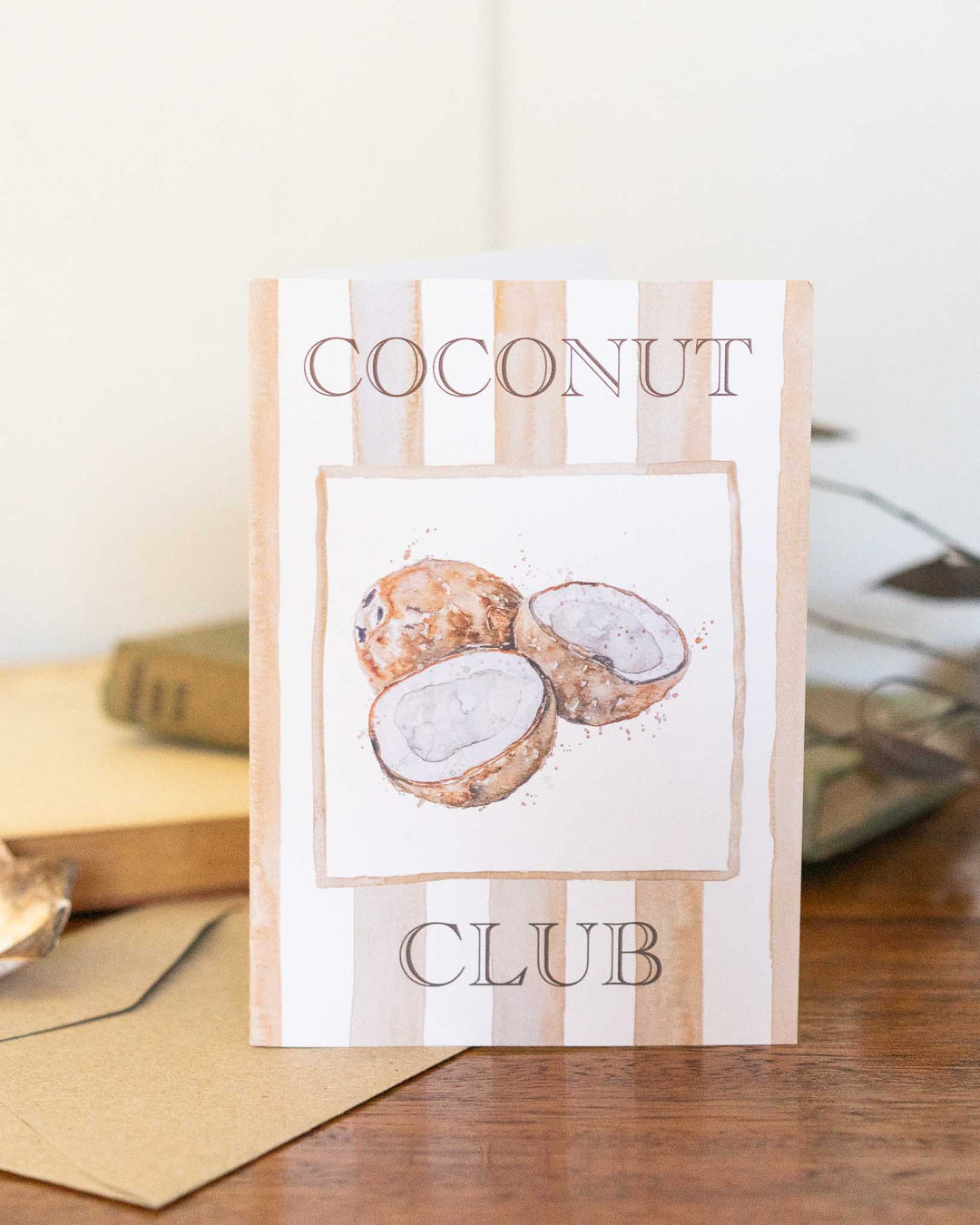 Coconut Club greeting card showing three cracked coconuts resting on a wooden surface.