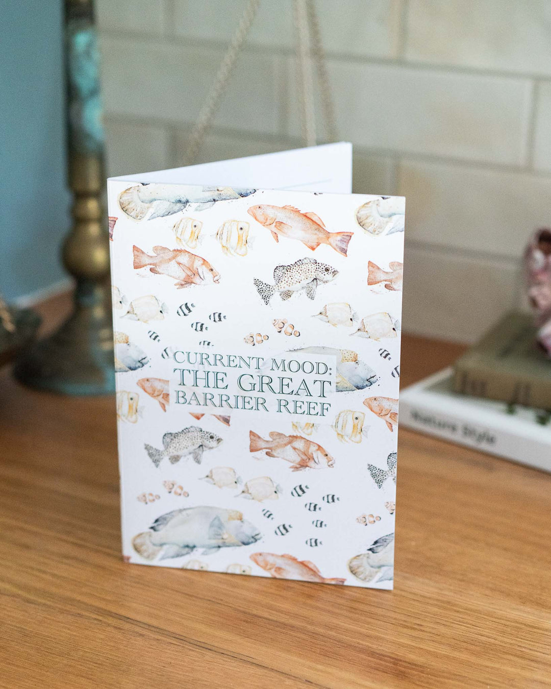 The Great Barrier Reef A5 notebook lies closed on a wooden desk, featuring colorful ocean-inspired cover art.
