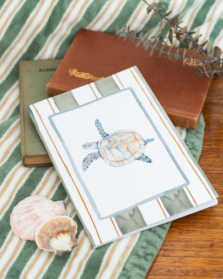 Follow Me A5 lined notebook on striped fabric, surrounded by seashells and vintage books.