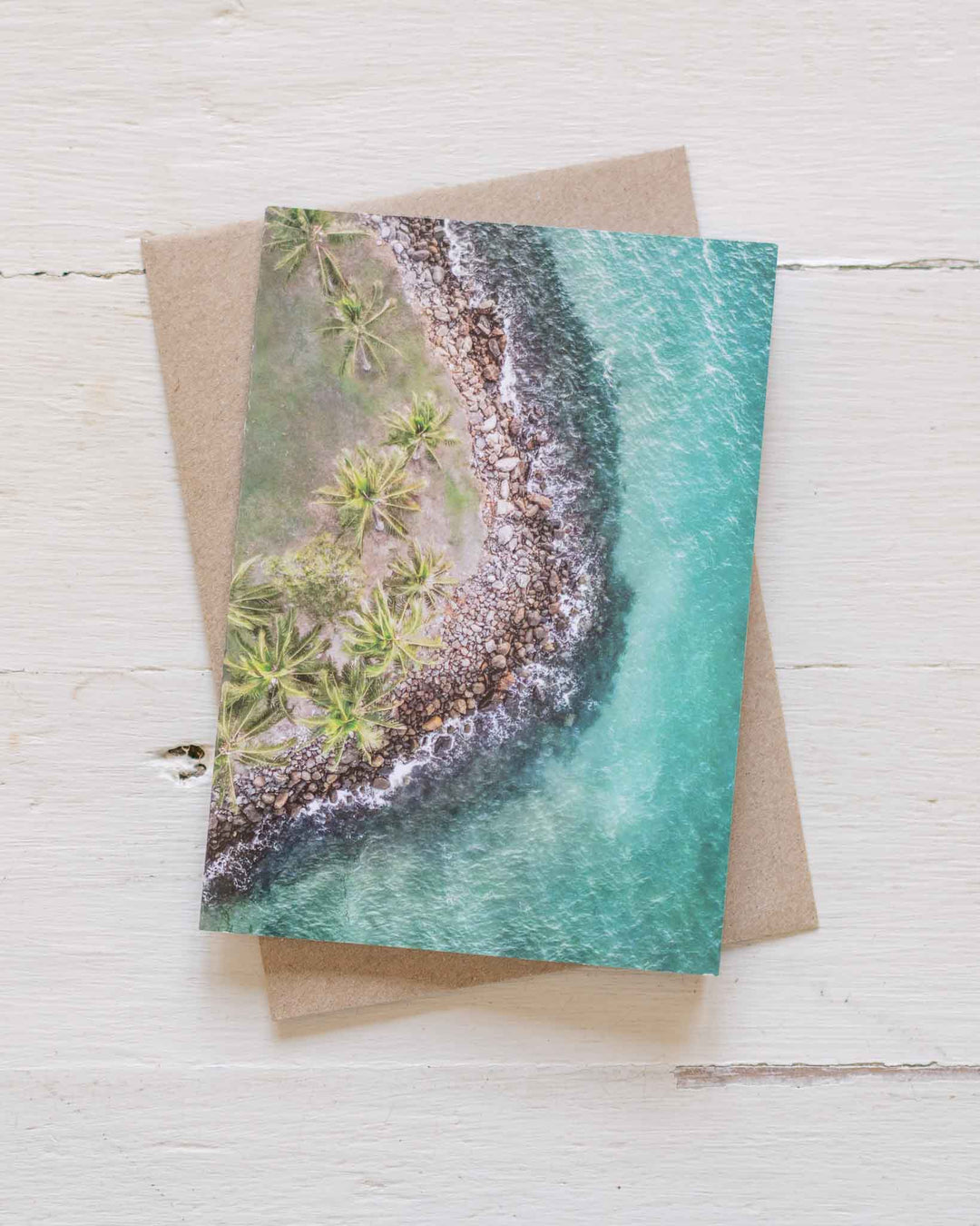 Hammocks and Hangouts greeting card showing a tropical shoreline, paired with a brown envelope.