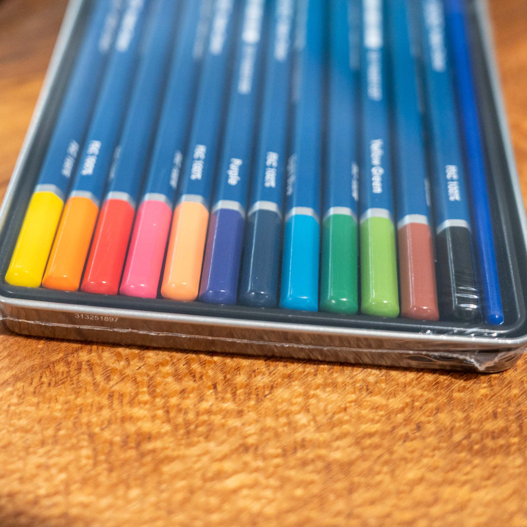 SEA Gallery Jasart 12 Watercolour Pencil Set tin, pencils spread out neatly on a wooden table.