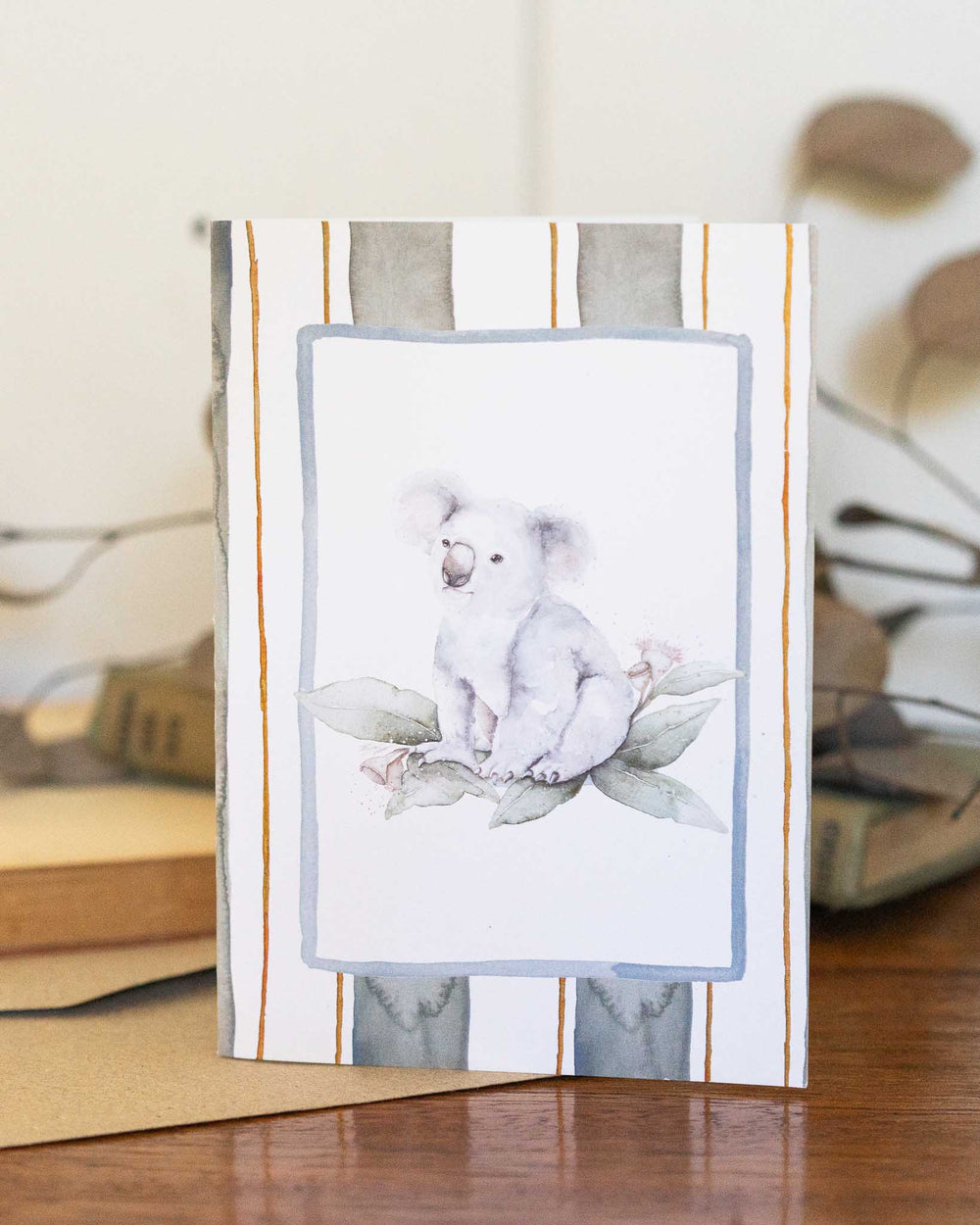 Koala Bloom Greeting Card showing a cute koala surrounded by green leaves, designed by Stephanie Elizabeth.