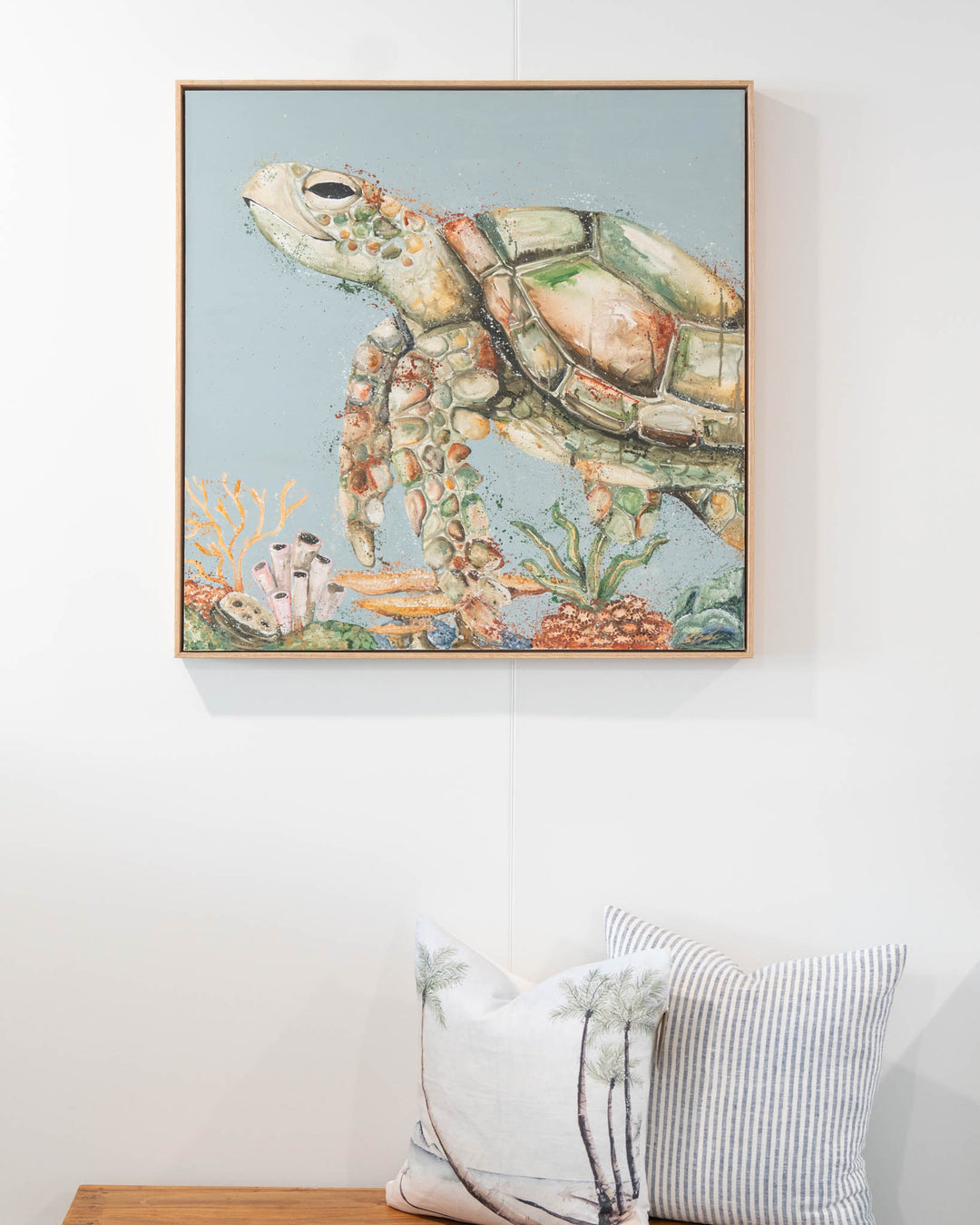 Lazy Days on Coral Cays“ artwork above a bench topped with two decorative pillows.