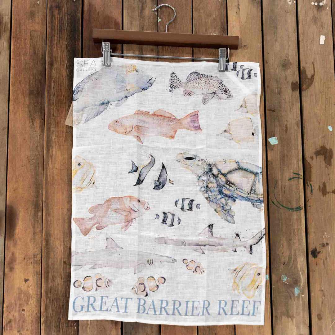 The Great Barrier Reef Linen Tea Towel decorated with colorful watercolor sea animals on a soft fabric background.