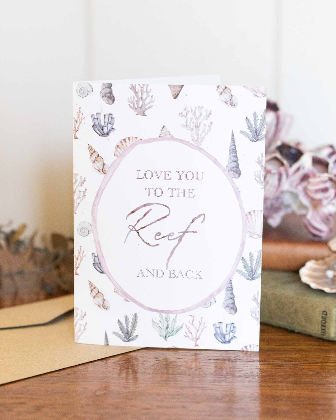 Love you to the Reef greeting card with sea-inspired watercolor art resting on a wooden table.