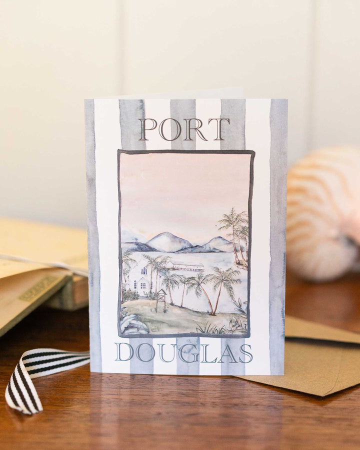 Port Douglas greeting card with envelopes and a seashell arranged on a tabletop.