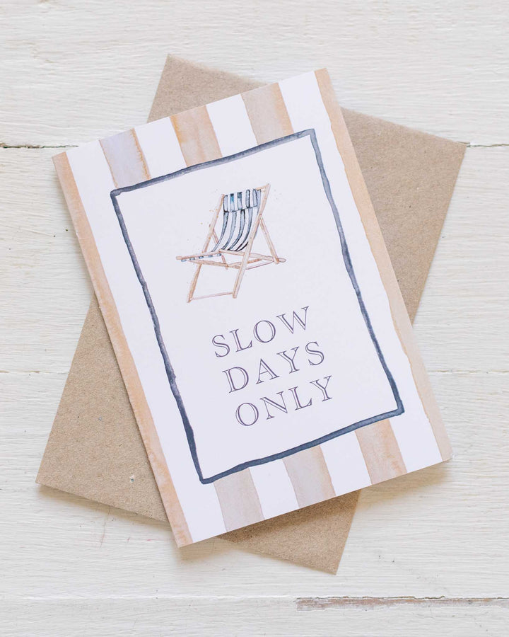 Slow Days Only greeting card featuring a watercolor striped deck chair and text on a wood-textured background.