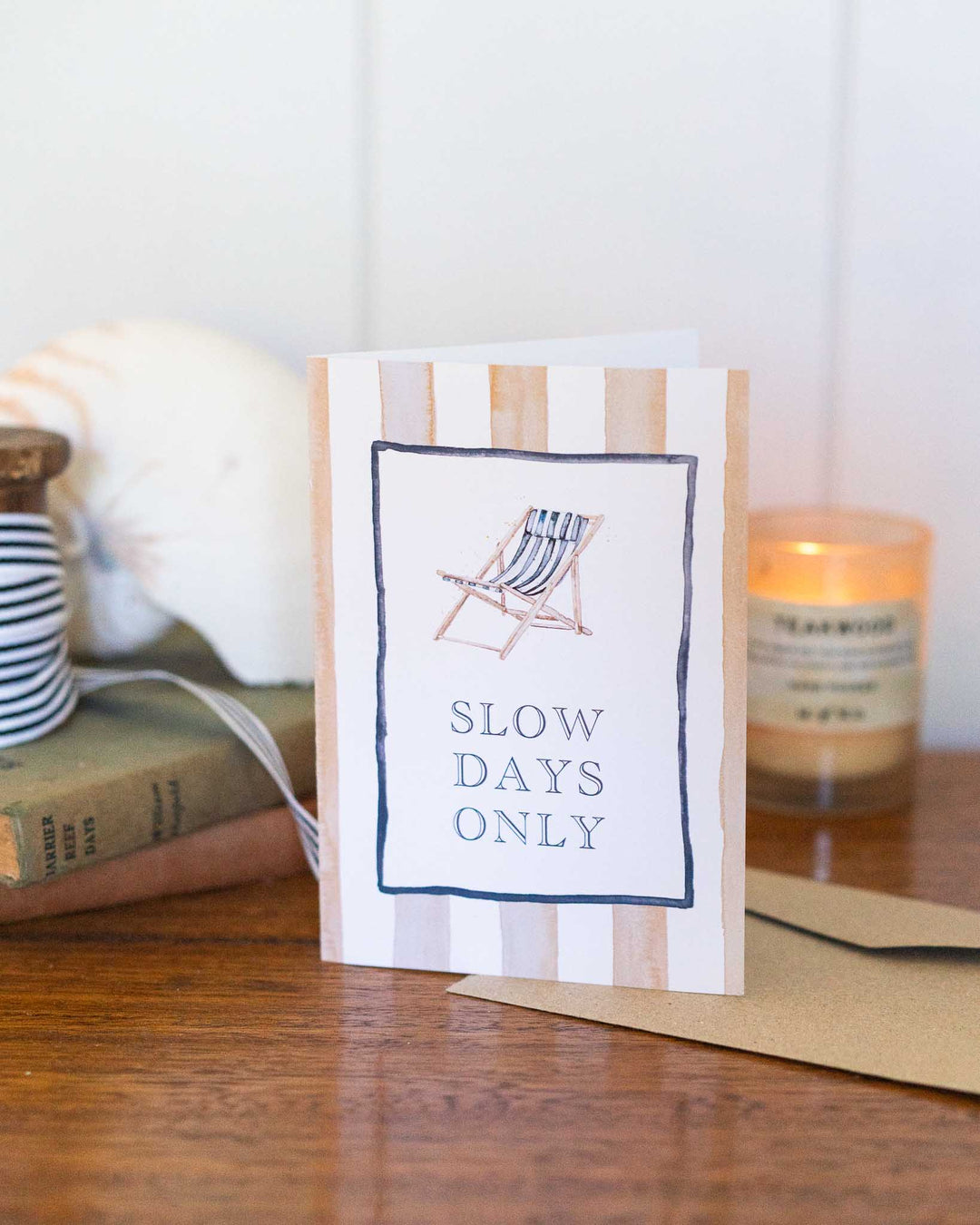 “Slow Days Only” card with a watercolor striped deck chair, resting on a wooden table.