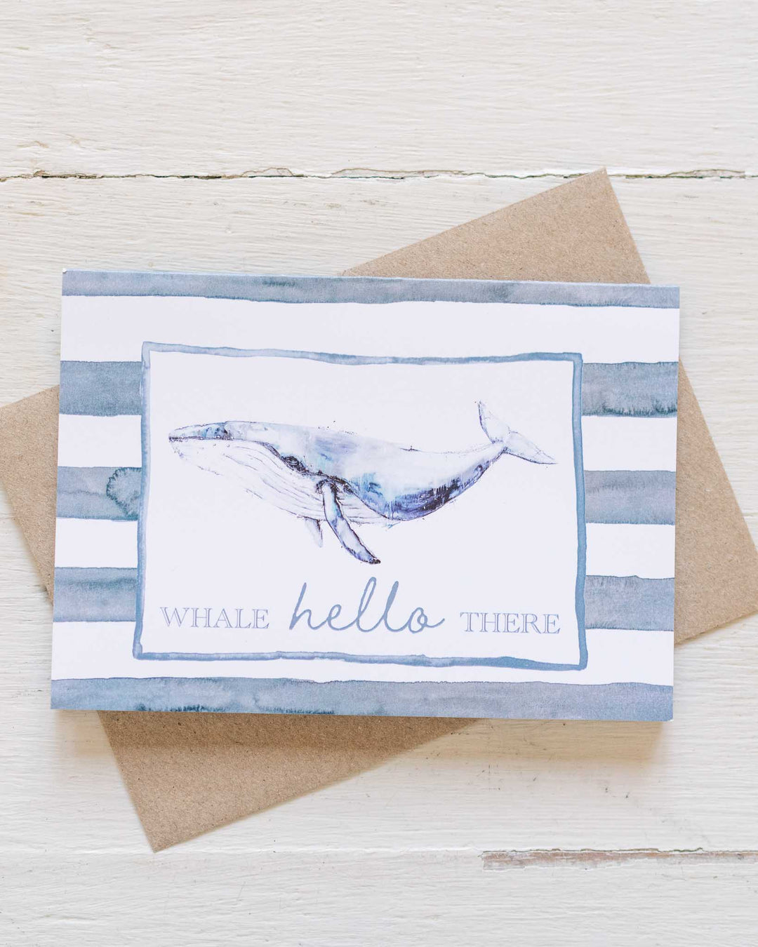 Whale Hello There greeting card with a blue whale illustration and striped background, in an eco-friendly envelope.