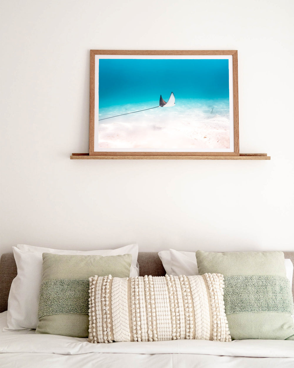 A Fleeting Moment – Eagle Ray, Underwater Photography by David Lloyd, framed paper print in oak frame, styled in a bedroom setting
