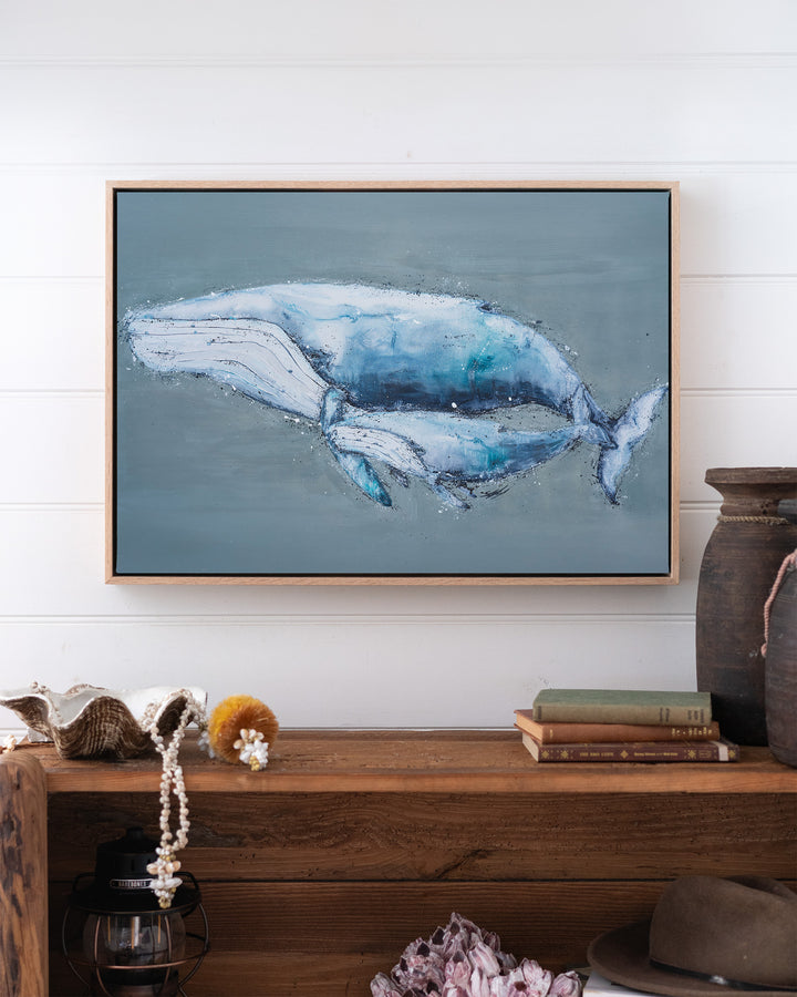 A Life Growing Together humpback whales fine art print by Stephanie Elizabeth, framed canvas in an oak frame above a bookshelf