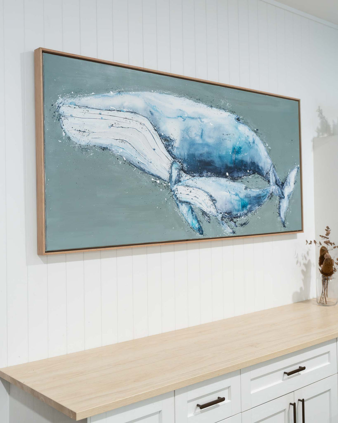 A Life Growing Together artwork hangs above a light wood counter with white cabinets below.