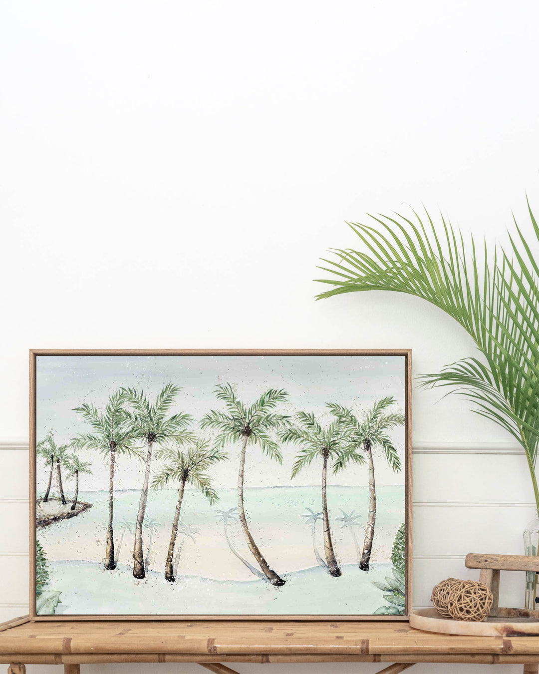 A Little Cove Love Story Port Douglas landscape fine art print by Stephanie Elizabeth, framed canvas in an oak frame above a console table