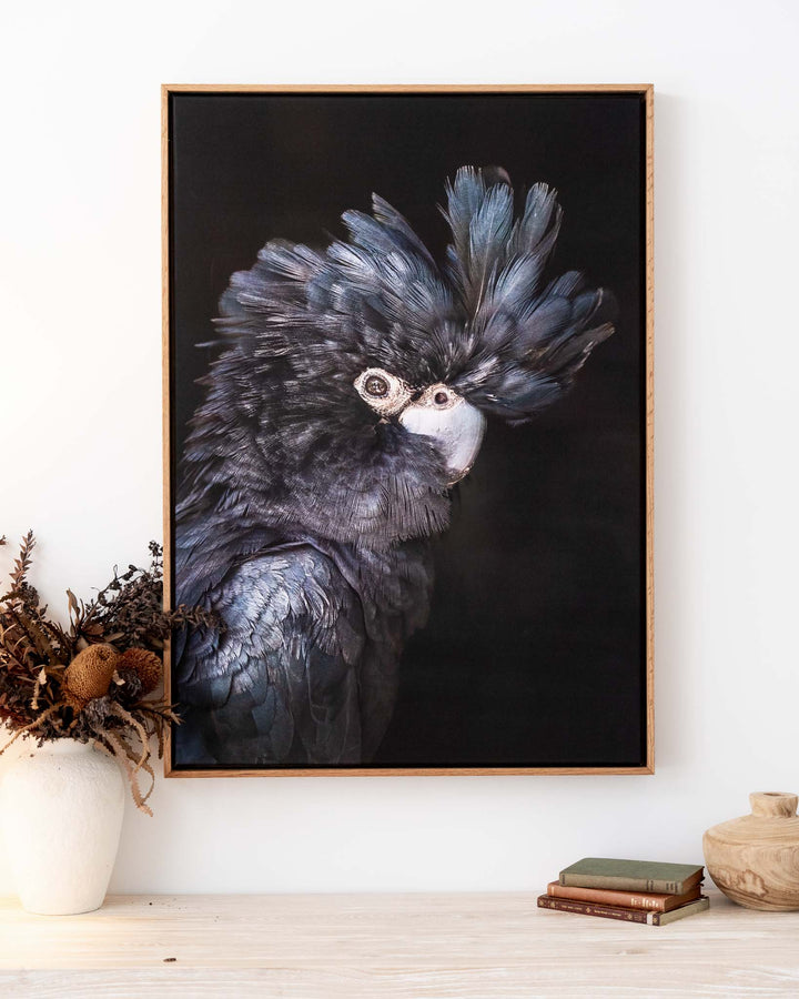 A Little More Action“ Black Cockatoo artwork framed above a sleek table with modern decor accents.