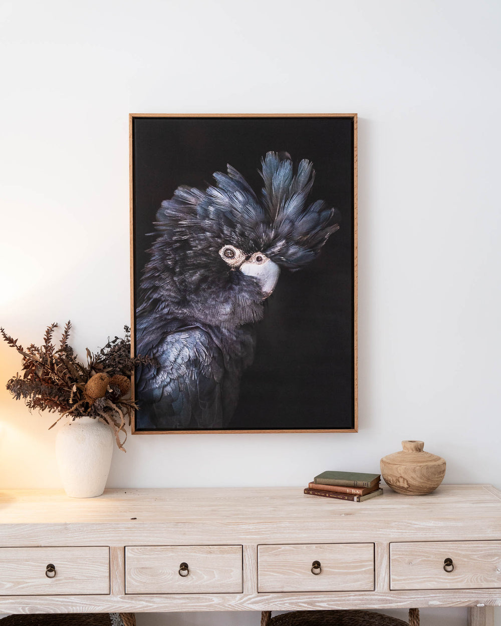 A Little More Action | Black Cockatoo artwork above a light wood desk with vintage decorative accents.