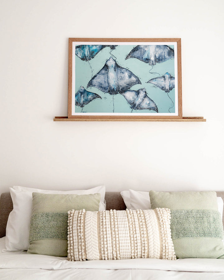 A Sea of Spots eagle rays fine art print by Stephanie Elizabeth, framed paper print in an oak frame in a bedroom