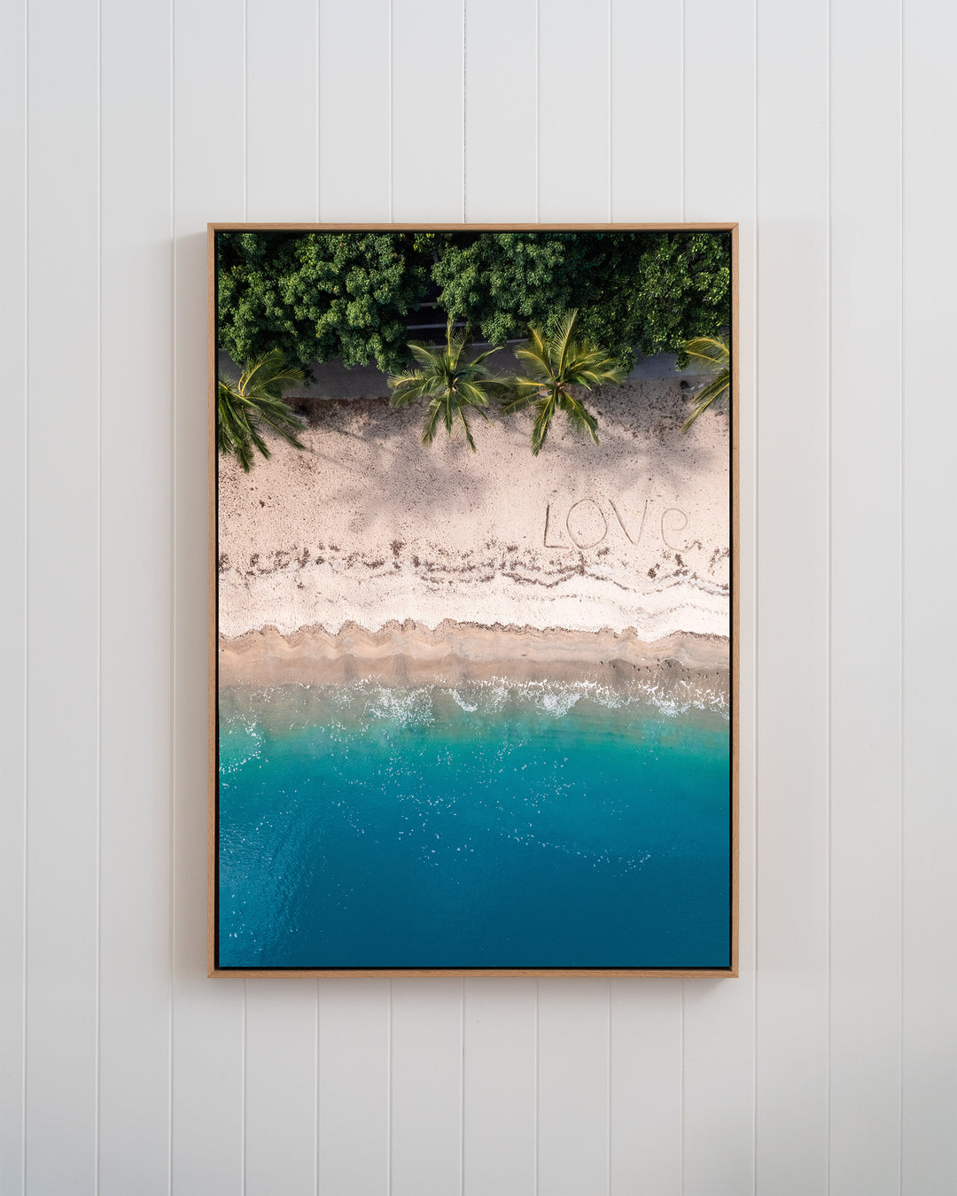 Framed aerial photography titled All You Need Is... showing the word LOVE written in the sand of the Whitsundays.