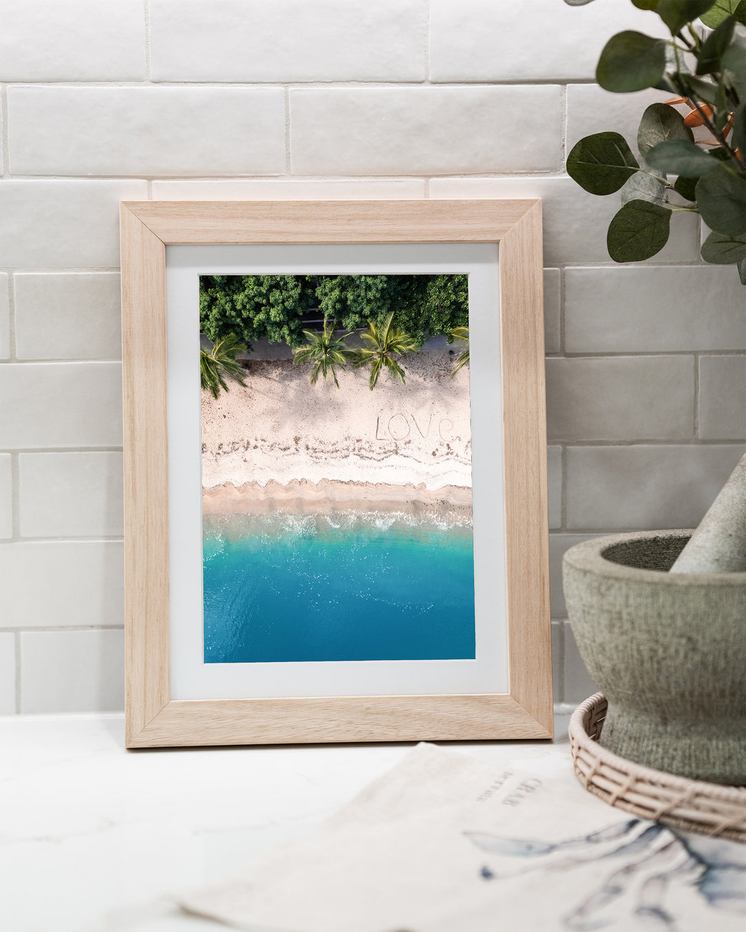 All You Need Is... – Whitsundays, Aerial Photography by David Lloyd, framed paper print in oak frame, styled in a kitchen bench setting