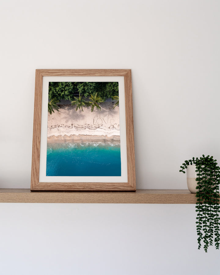 All You Need Is... – Whitsundays, Aerial Photography by David Lloyd, framed paper print in oak frame, styled in a timber shelf setting