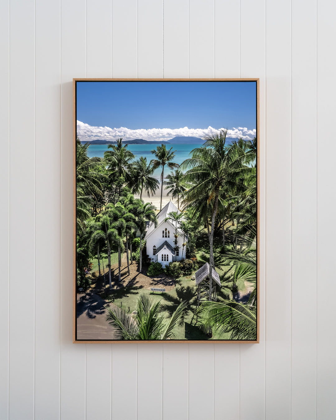 Always Forever print of St Mary’s, Port Douglas: an aerial view of a white church by a tropical beach in a white frame.