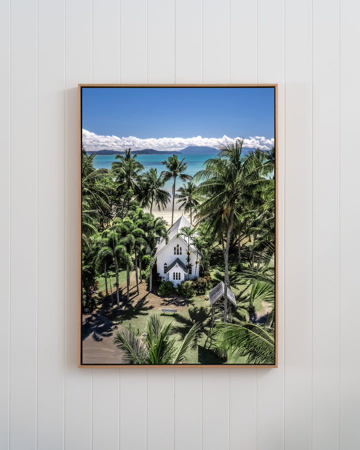 Always Forever print of St Mary’s, Port Douglas: an aerial view of a white church by a tropical beach in a white frame.
