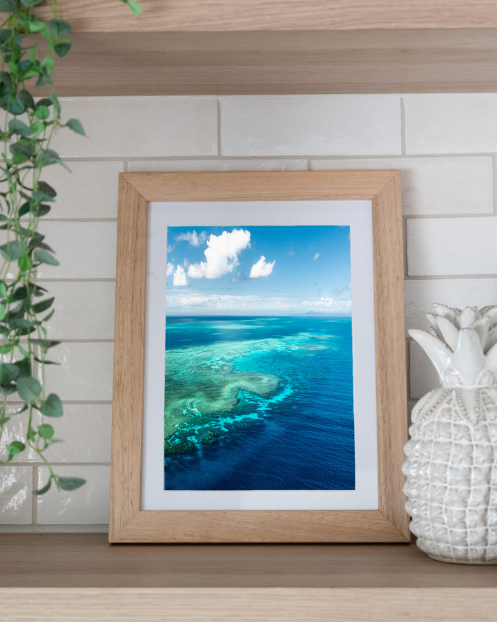 Always Take The Weather With You – Rudder Reef, Aerial Photography by David Lloyd, framed paper print in oak frame, styled in a kitchen shelf setting