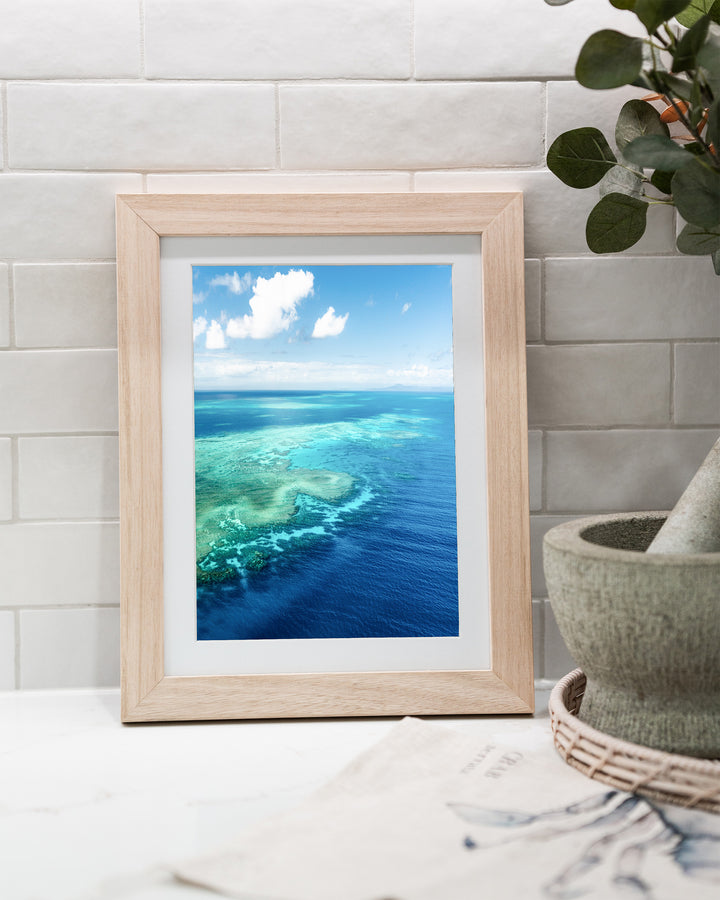 Always Take The Weather With You – Rudder Reef, Aerial Photography by David Lloyd, framed paper print in oak frame, styled in a kitchen bench setting