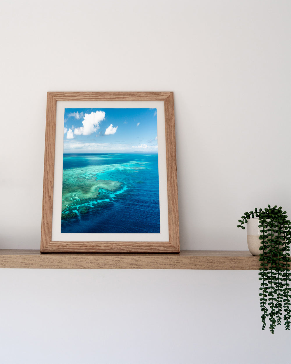Always Take The Weather With You – Rudder Reef, Aerial Photography by David Lloyd, framed paper print in oak frame, styled in a timber shelf setting
