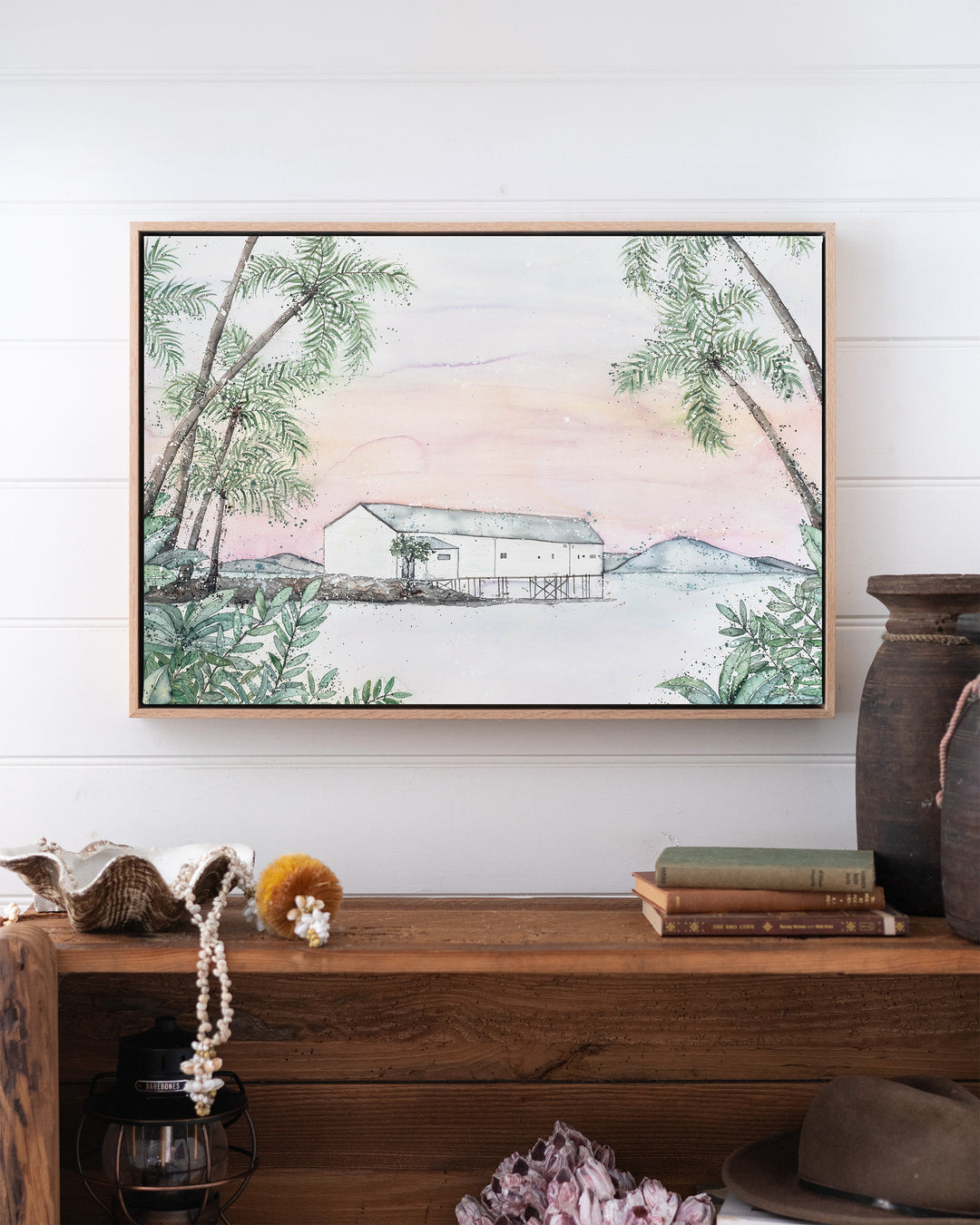 Balmy Beachside Sugar Wharf Port Douglas fine art print by Stephanie Elizabeth, framed canvas in an oak frame above a bookshelf
