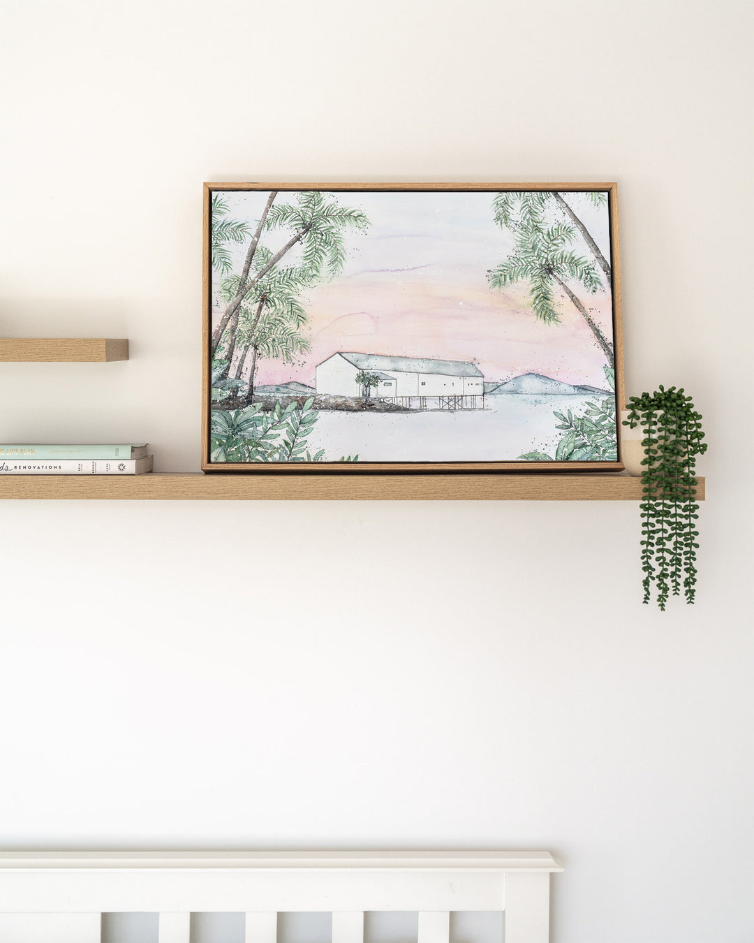Balmy Beachside Sugar Wharf Port Douglas fine art print by Stephanie Elizabeth, framed canvas in an oak frame on a shelf