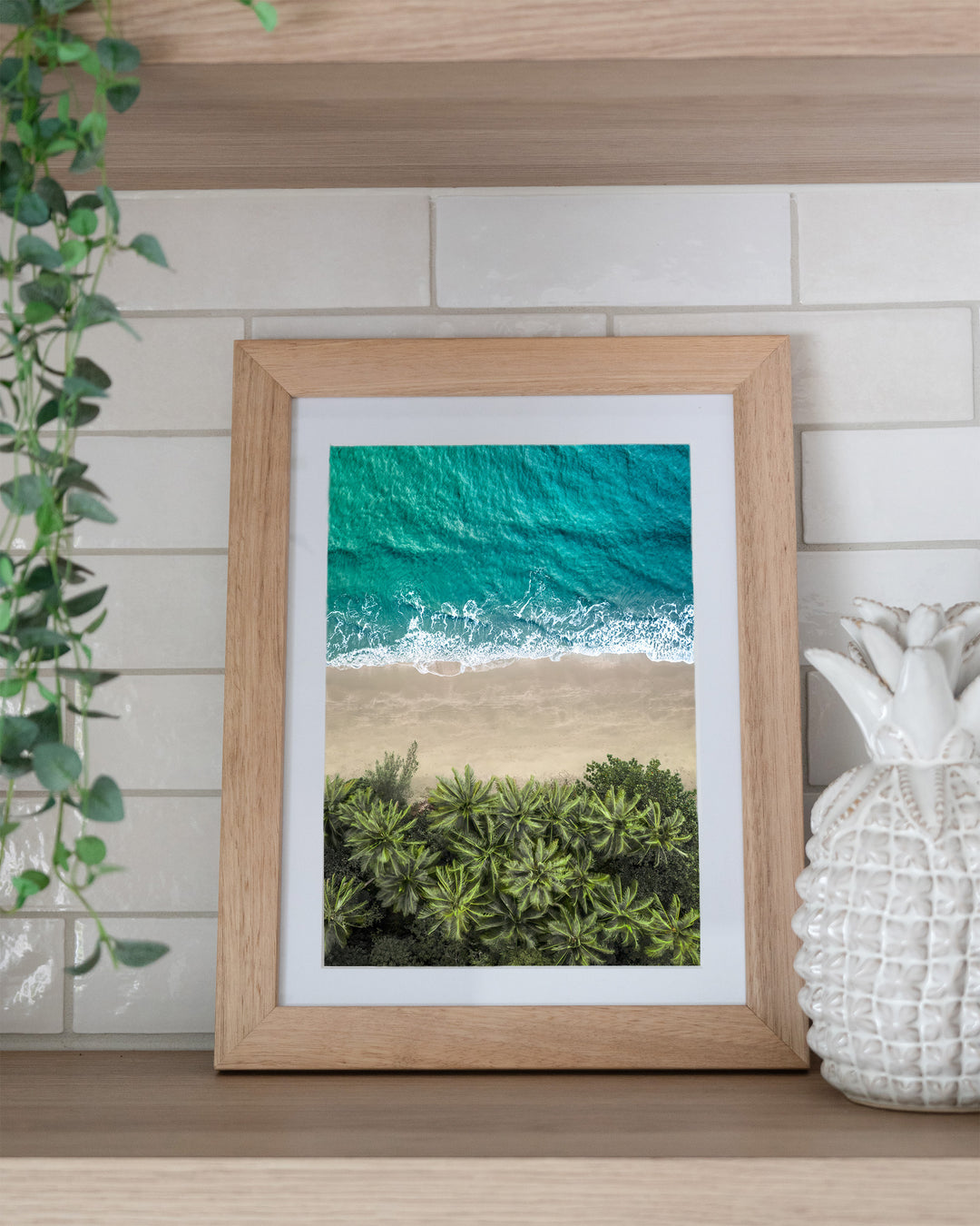 Beachside Reverie – Four Mile Beach, Aerial Photography by David Lloyd, framed paper print in oak frame, styled in a kitchen shelf setting