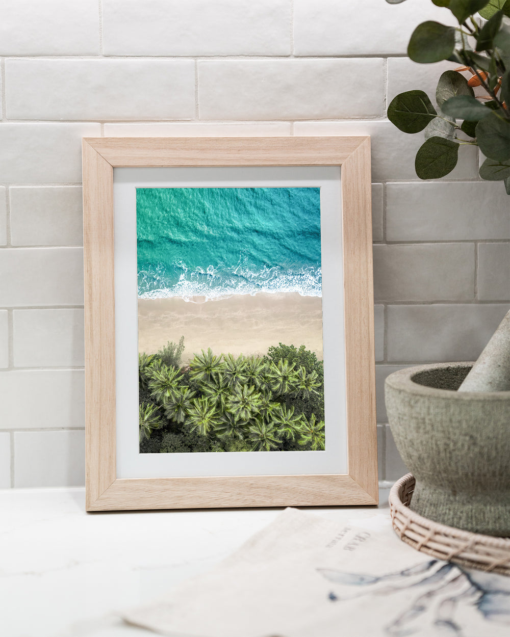 Beachside Reverie – Four Mile Beach, Aerial Photography by David Lloyd, framed paper print in oak frame, styled in a kitchen bench setting