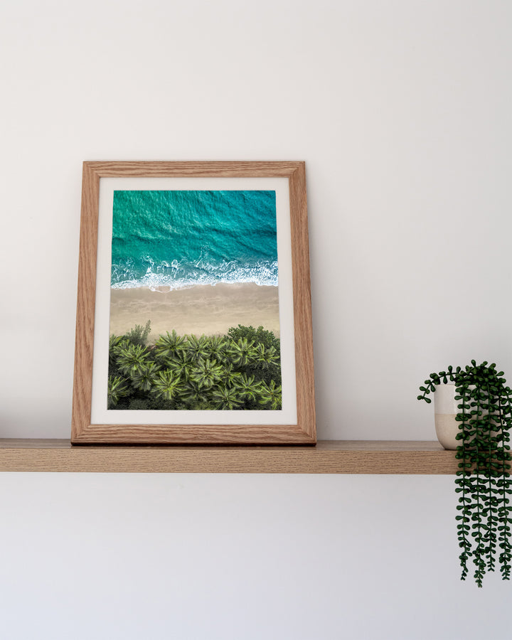 Beachside Reverie – Four Mile Beach, Aerial Photography by David Lloyd, framed paper print in oak frame, styled in a timber shelf setting
