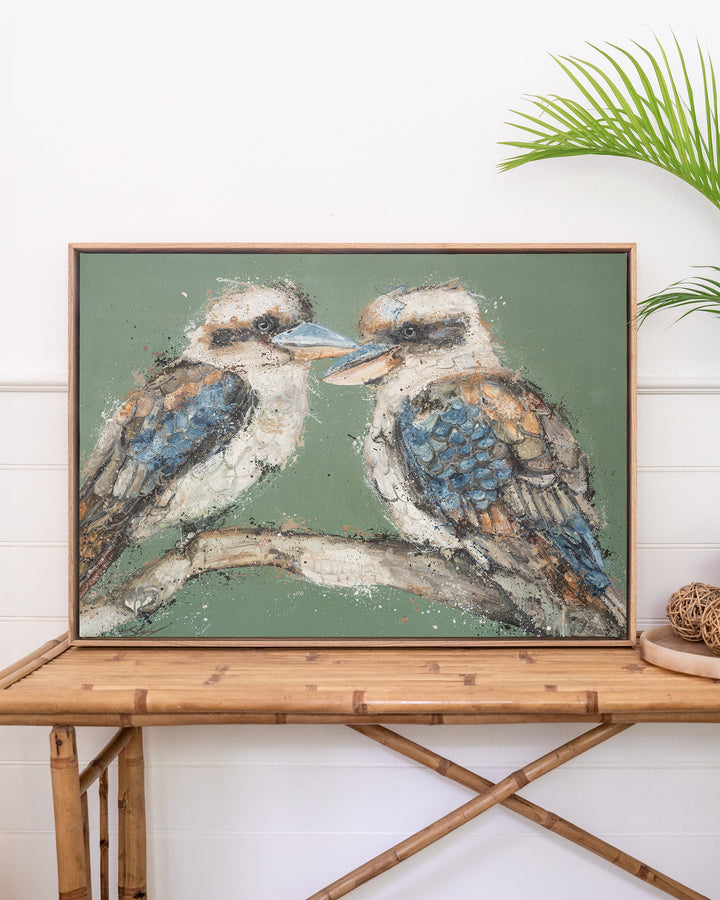 Beaks and Bedlam kookaburra fine art print by Stephanie Elizabeth, framed canvas in an oak frame above a rattan table