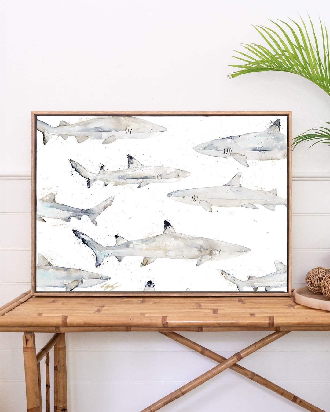 Black or White reef sharks fine art print by Stephanie Elizabeth, framed canvas in an oak frame above a rattan table