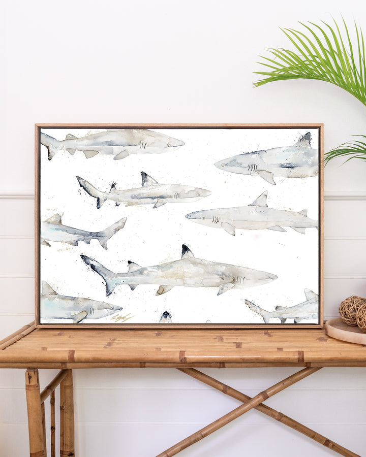 Black or White reef sharks fine art print by Stephanie Elizabeth, framed canvas in an oak frame above a rattan table