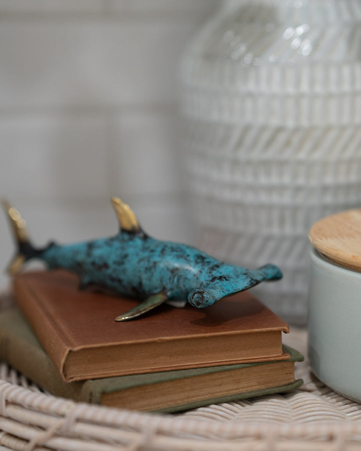 Hammerhead Shark sculpture in aged brass displayed on stacked books beside a vase.