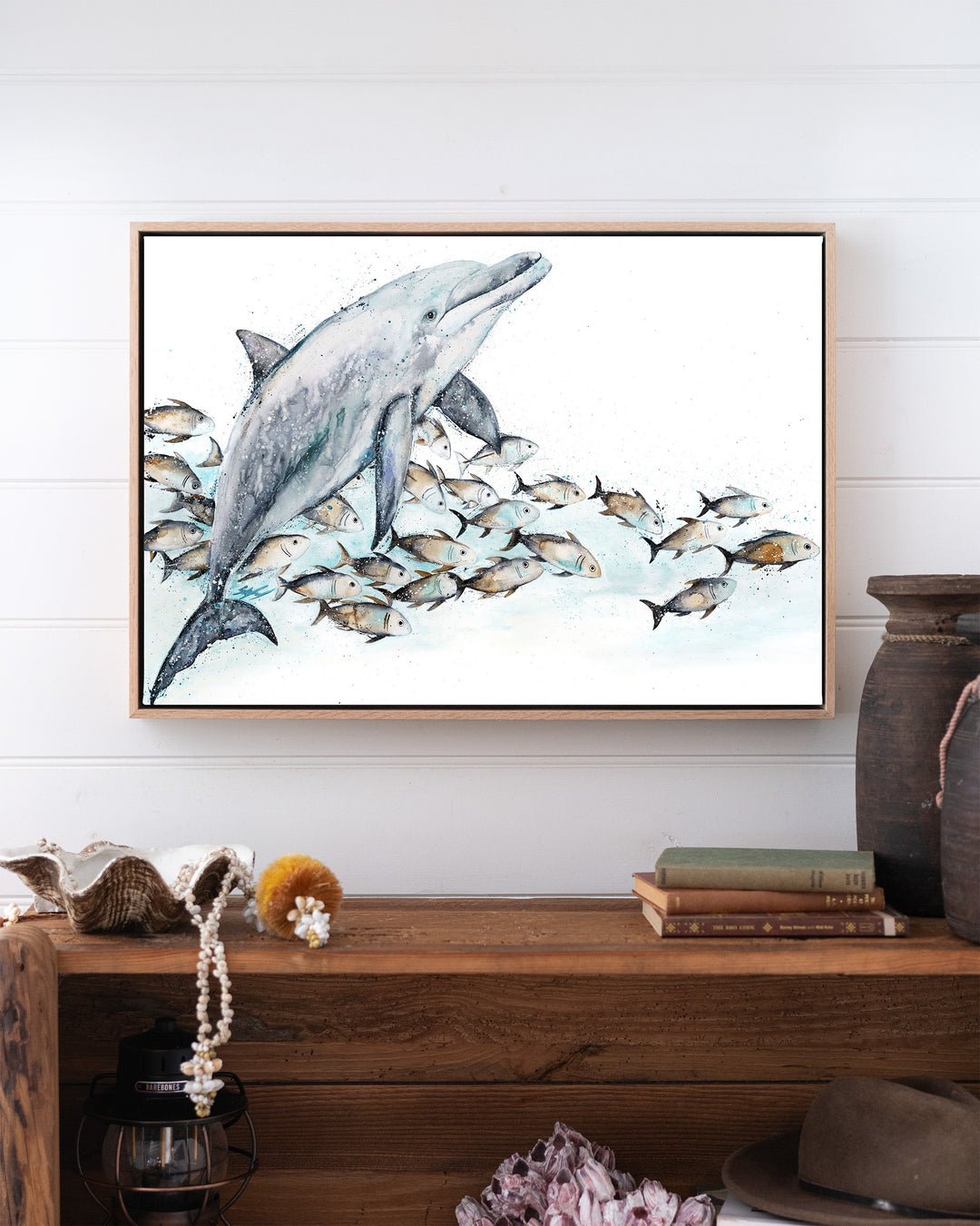 Bubble Toes – dolphin with a school of fish, framed canvas in oak float frame, styled above a timber console