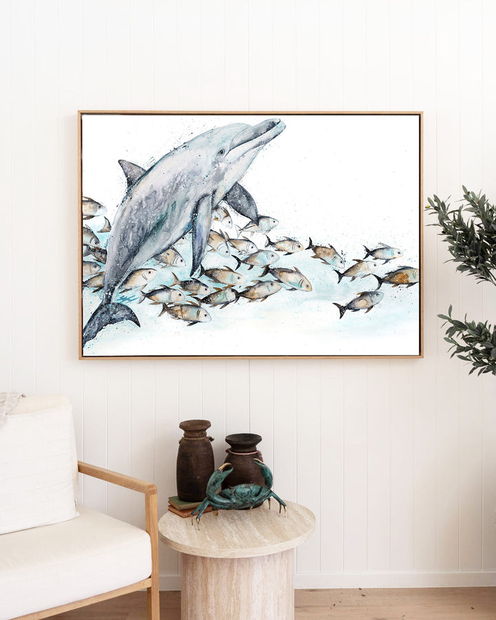 Bubble Toes – dolphin with a school of fish, framed canvas in oak float frame, styled in a living room
