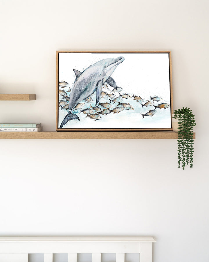 Bubble Toes – dolphin with a school of fish, framed canvas in oak float frame, styled on a floating shelf