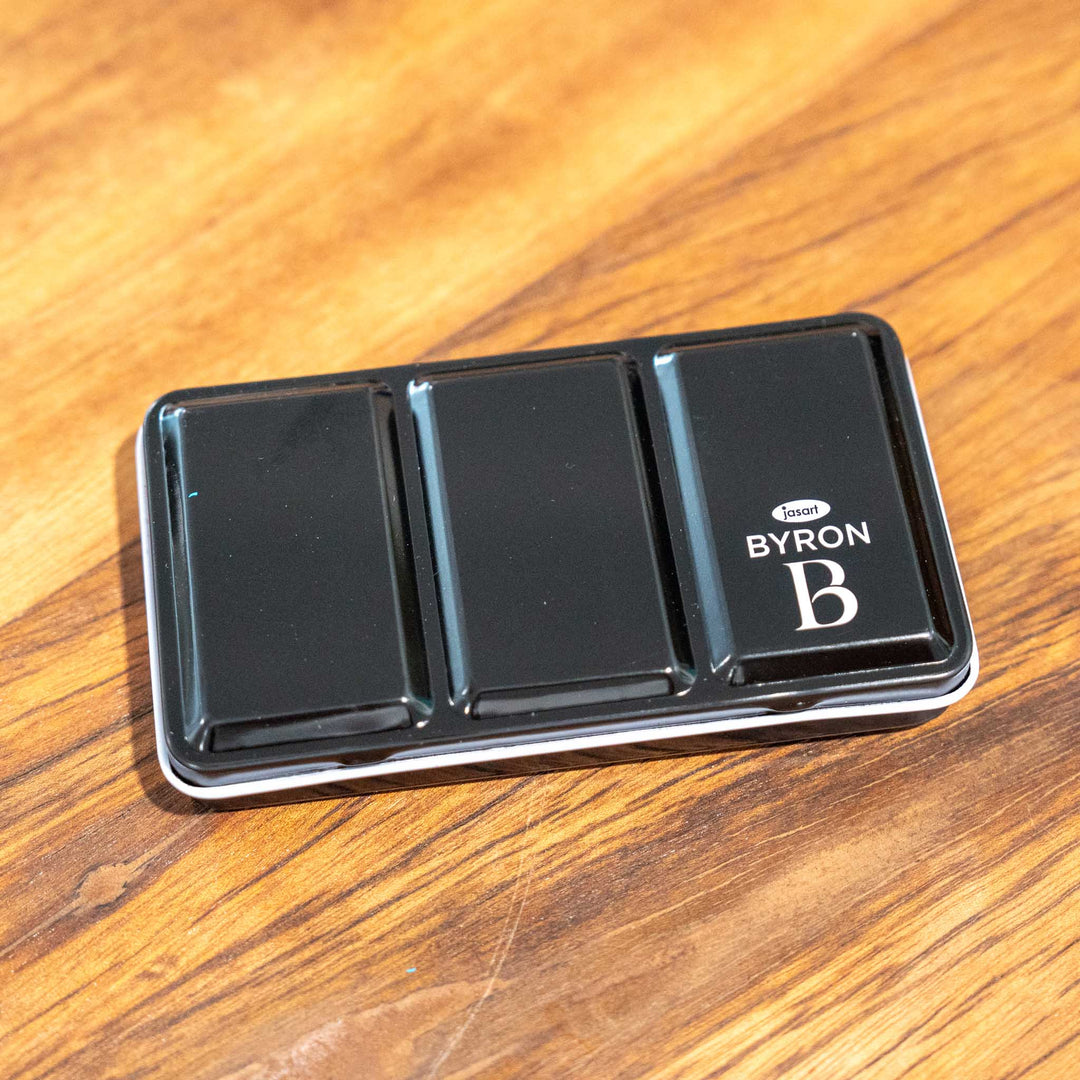 SEA Gallery Nature Watercolour Pocket Set case, divided into three sections, resting on a wooden surface.