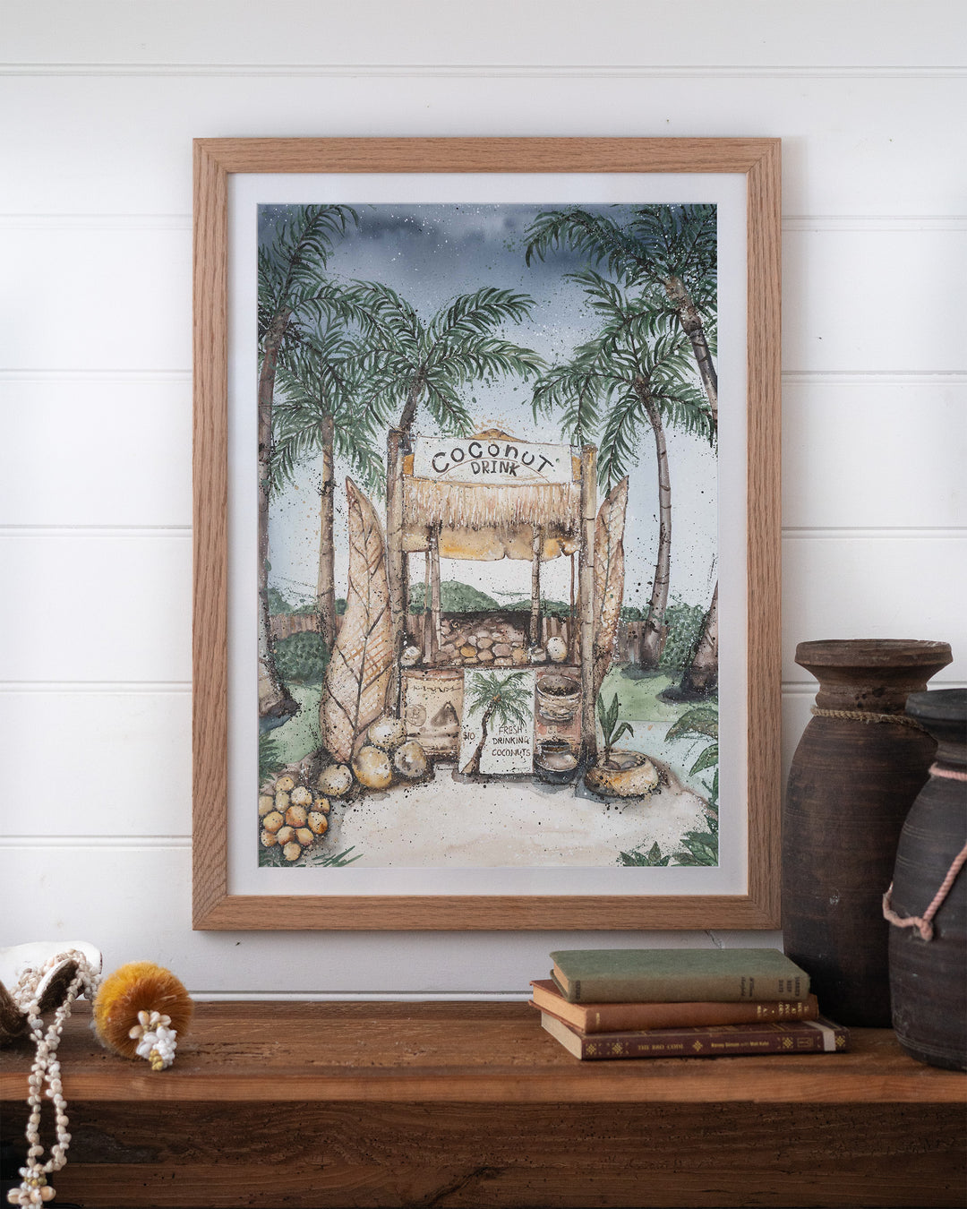 Coconut Hut tropical still life fine art print by Stephanie Elizabeth, framed paper print in an oak frame on a shelf