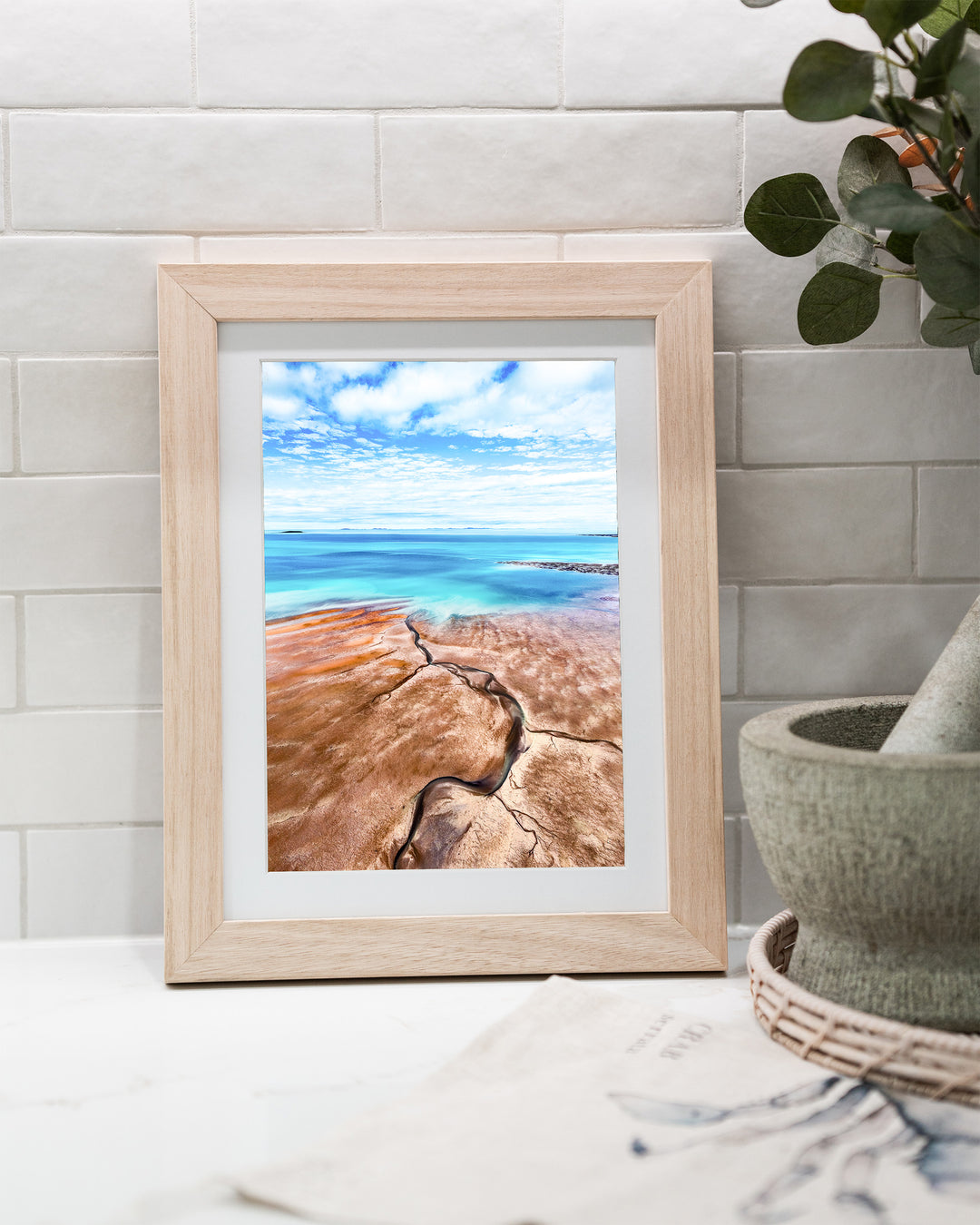 Cracks in the Ocean – Ocean Art, Aerial Photography by David Lloyd, framed paper print in oak frame, styled in a kitchen bench setting